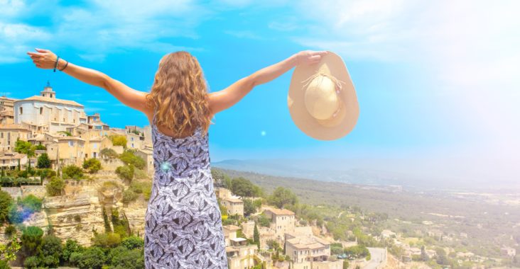 femme ouvrant les bras devant une vue sur le village de Gordes dans la région PACA