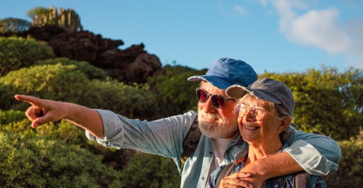 couple de retraités souriant en vacances observant le couché de soleil